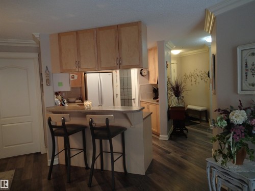 The kitchen features light wood cabinetry, a breakfast bar. - 206 10208 120 Street, Edmonton, AB - Indoor