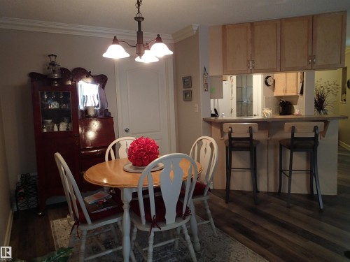 The dining area features laminate flooring, a chandelier, and a built-in breakfast bar with cabinetry - 206 10208 120 Street, Edmonton, AB - Indoor Photo Showing Dining Room
