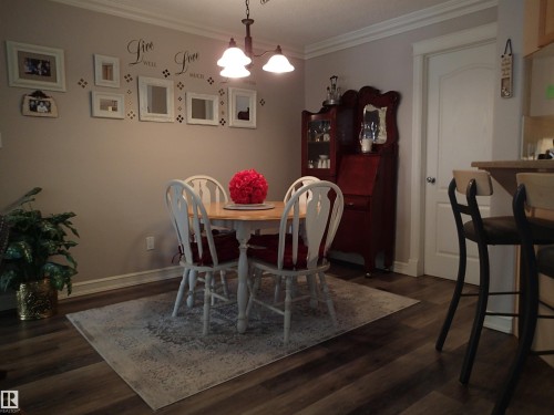 The dining area features laminate flooring and crown molding - 206 10208 120 Street, Edmonton, AB - Indoor Photo Showing Dining Room