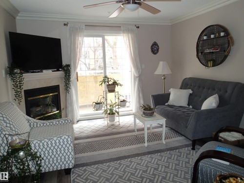Living room featuring crown molding, a fireplace with a mantel, and a ceiling fan - 206 10208 120 Street, Edmonton, AB - Indoor Photo Showing Living Room With Fireplace