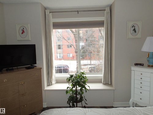 The property features a large window with white muntins and a window seat - 206 10208 120 Street, Edmonton, AB - Indoor Photo Showing Bedroom