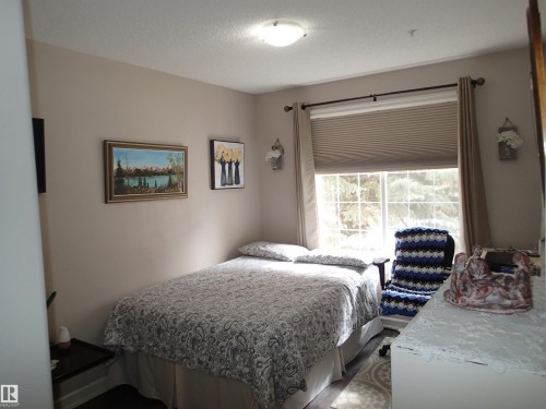 The room features a window with blinds and curtains, offering natural light - 206 10208 120 Street, Edmonton, AB - Indoor Photo Showing Bedroom