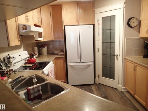 The efficient kitchen features light wood cabinetry and is open to an eating bar. - 206 10208 120 Street, Edmonton, AB - Indoor Photo Showing Kitchen With Double Sink