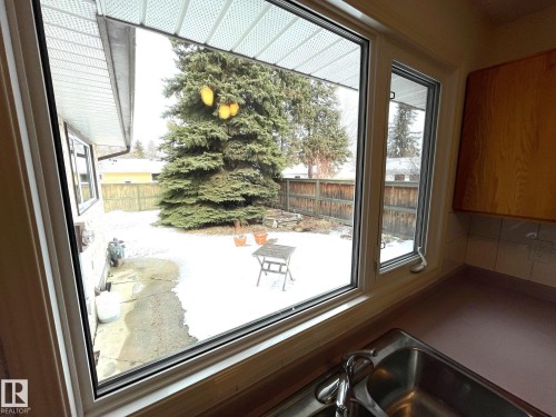 Kitchen sink area with a window overlooking the backyard, which features a mature evergreen tree and a wooden fence - 44 Arlington Drive, St. Albert, AB - Indoor