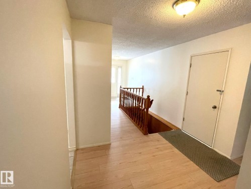 This property features light-toned flooring, a light-colored entry door, and a traditional wooden railing - 44 Arlington Drive, St. Albert, AB - Indoor Photo Showing Other Room