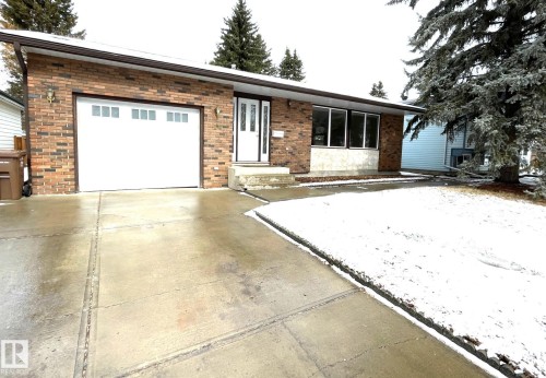 The property features a brick exterior, an integrated garage with a white door, and a concrete driveway - 44 Arlington Drive, St. Albert, AB - Outdoor