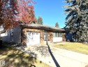 The property features a brick exterior with a white garage door, a concrete driveway, and a front yard with grass and mature trees - 44 Arlington Drive, St. Albert, AB  - Outdoor 