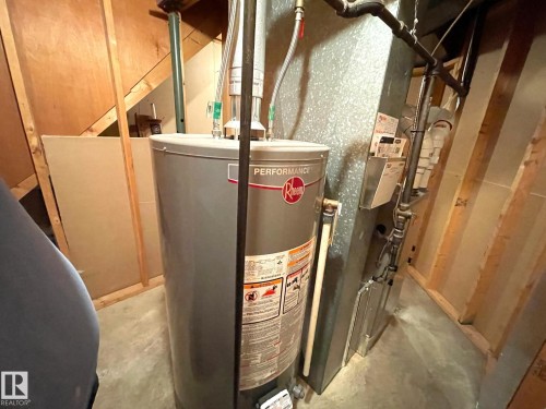 The property features a water heater and a furnace, installed within a utility space with exposed wood framing - 44 Arlington Drive, St. Albert, AB - Indoor Photo Showing Basement