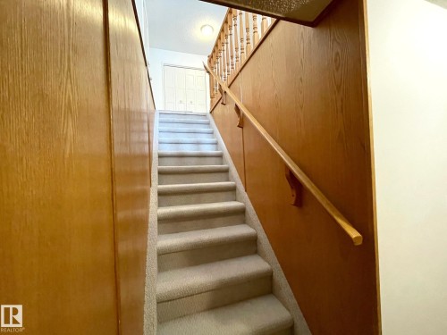 Staircase featuring carpeted steps, a wooden handrail, and wood paneling on the walls - 44 Arlington Drive, St. Albert, AB - Indoor Photo Showing Other Room