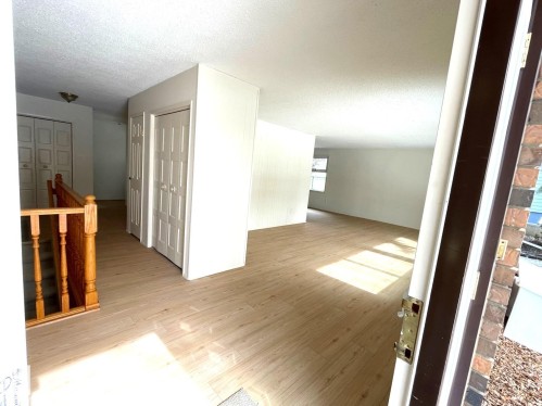 Welcoming entryway with light wood-style flooring and white walls, featuring a wooden banister and white paneled doors - 44 Arlington Drive, St. Albert, AB - Indoor Photo Showing Other Room