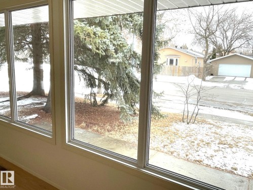 The property features large picture windows providing views of the surrounding outdoor area with trees and a street - 44 Arlington Drive, St. Albert, AB - Indoor Photo Showing Other Room