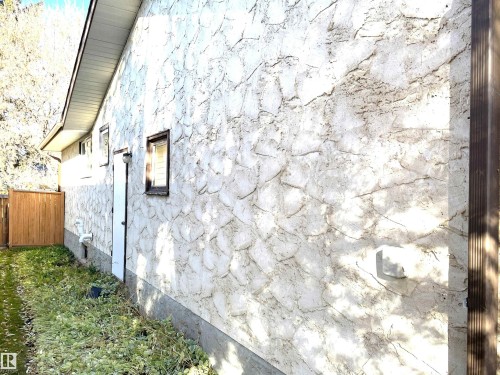 The property features an exterior with textured stucco siding, a brown wooden fence, and a green lawn area - 44 Arlington Drive, St. Albert, AB - Outdoor