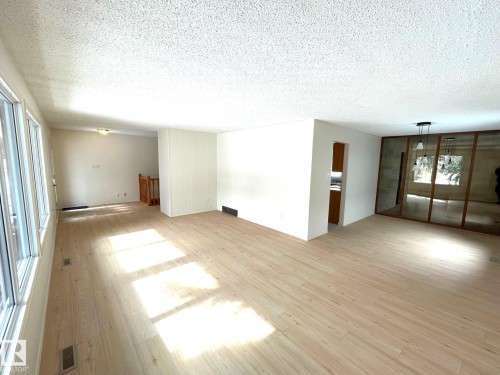 Spacious living area featuring light-toned flooring, large windows, and a ceiling light fixture - 44 Arlington Drive, St. Albert, AB - Indoor Photo Showing Other Room