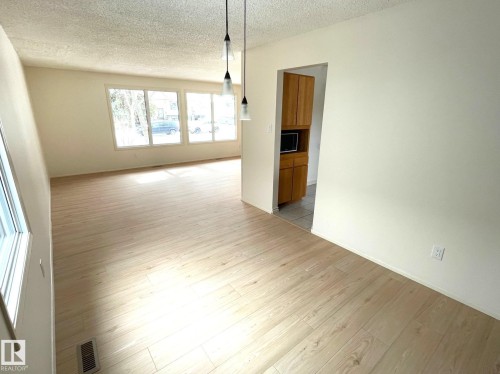 This bright interior space features light-colored flooring throughout, large windows, and pendant lighting fixtures - 44 Arlington Drive, St. Albert, AB - Indoor Photo Showing Other Room