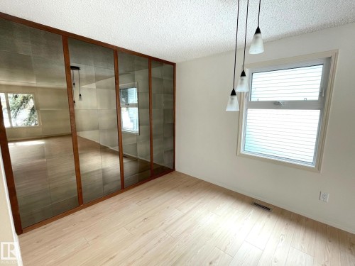 Bright room featuring light-toned flooring, a window with blinds, and mirrored wall panels with a wooden frame - 44 Arlington Drive, St. Albert, AB - Indoor Photo Showing Other Room