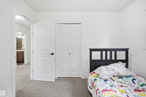 This room features light-colored carpeting, white walls, and a white bi-fold closet door - 469 Ainslie Crescent Sw, Edmonton, AB - Indoor Photo Showing Bedroom