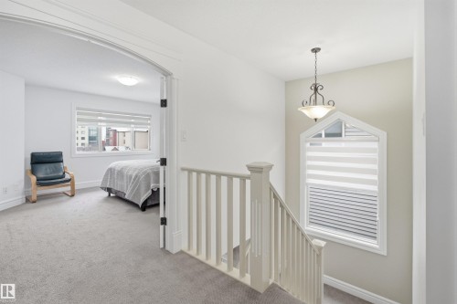 This property features light-colored walls and carpet throughout, with a bedroom visible through an arched doorway - 469 Ainslie Crescent Sw, Edmonton, AB - Indoor Photo Showing Bedroom