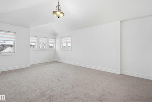Spacious room featuring light-colored carpet, white walls, and multiple windows with blinds providing natural light - 469 Ainslie Crescent Sw, Edmonton, AB - Indoor Photo Showing Other Room