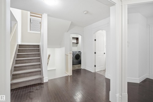 The property features dark hardwood flooring and a carpeted staircase with white railings - 469 Ainslie Crescent Sw, Edmonton, AB - Indoor Photo Showing Other Room