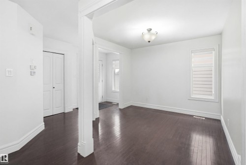 This inviting interior features dark hardwood flooring and white walls throughout - 469 Ainslie Crescent Sw, Edmonton, AB - Indoor Photo Showing Other Room