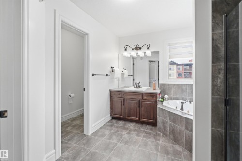 Bathroom featuring a tiled floor, a vanity with a sink and storage, a corner bathtub, and a separate shower enclosure - 469 Ainslie Crescent Sw, Edmonton, AB - Indoor Photo Showing Bathroom