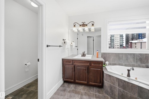 Bathroom featuring a corner soaking tub, a vanity with a rectangular sink, and tiled floors - 469 Ainslie Crescent Sw, Edmonton, AB - Indoor Photo Showing Bathroom