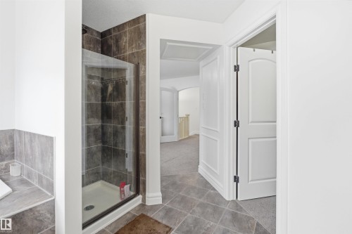 Bathroom featuring a glass-enclosed shower with dark tiled walls, and a tiled floor - 469 Ainslie Crescent Sw, Edmonton, AB - Indoor Photo Showing Bathroom