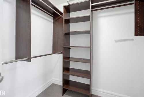 The property features a closet with built-in dark wood shelving and hanging rods - 469 Ainslie Crescent Sw, Edmonton, AB - Indoor Photo Showing Other Room