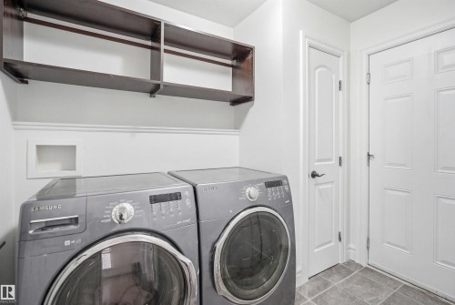 Laundry area featuring tile flooring, white walls, and dark wood shelving - 469 Ainslie Crescent Sw, Edmonton, AB - Indoor Photo Showing Laundry Room