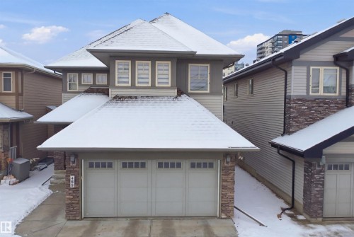 This property features a two-car garage with paneling and windows, a stone facade, and a multi-level roofline - 469 Ainslie Crescent Sw, Edmonton, AB - Outdoor