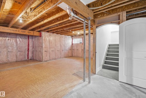 The unfinished basement features exposed wooden ceiling joists, insulated walls, and a staircase with carpeted treads - 469 Ainslie Crescent Sw, Edmonton, AB - Indoor Photo Showing Basement
