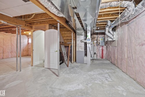 The basement features a concrete floor, exposed wooden beams, and visible ductwork - 469 Ainslie Crescent Sw, Edmonton, AB - Indoor Photo Showing Basement