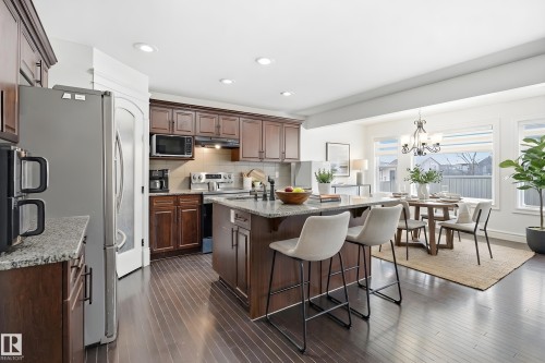 The kitchen features dark wood cabinetry, granite countertops, and stainless steel appliances - 469 Ainslie Crescent Sw, Edmonton, AB - Indoor