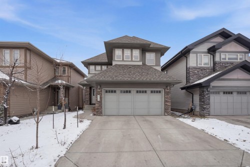 The property features a two-story exterior with stone accents and a concrete driveway leading to an attached two-car garage - 469 Ainslie Crescent Sw, Edmonton, AB - Outdoor With Facade