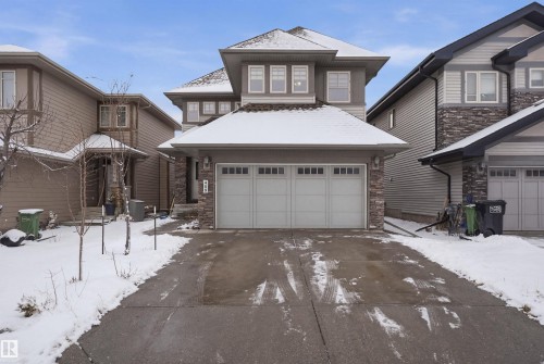 The property features a two-story design with a two-car garage, stone accents on the facade, and a paved driveway - 469 Ainslie Crescent Sw, Edmonton, AB - Outdoor