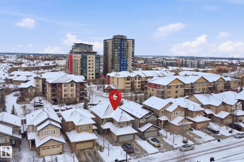 Overhead view of the property and its surrounding neighborhood, featuring multi-story residential buildings and detached homes with snow-covered rooftops - 469 Ainslie Crescent Sw, Edmonton, AB - Outdoor With Facade