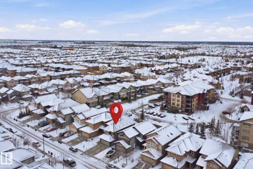 The property is situated within a residential neighborhood featuring detached homes and multi-story buildings, all with snow-covered roofs - 469 Ainslie Crescent Sw, Edmonton, AB - Outdoor With View