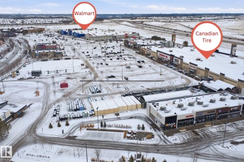 Aerial view of a commercial area featuring various retail buildings and expansive parking lots - 469 Ainslie Crescent Sw, Edmonton, AB - Outdoor With View