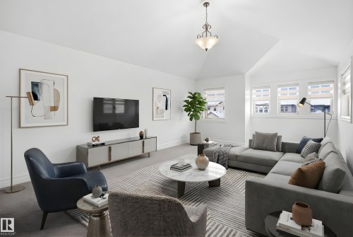 Living space featuring a vaulted ceiling with an elegant light fixture, soft gray carpeting, and multiple windows providing natural light - 469 Ainslie Crescent Sw, Edmonton, AB - Indoor Photo Showing Living Room