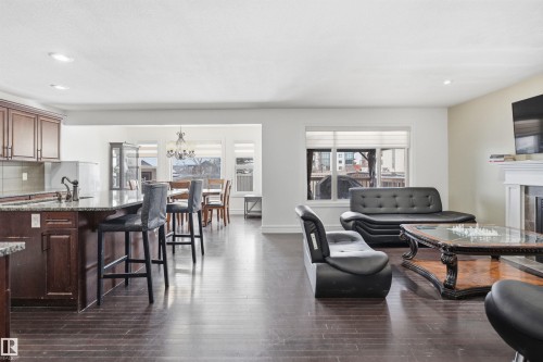 Open-concept living area featuring dark hardwood floors, recessed lighting, and a fireplace with a white mantel - 469 Ainslie Crescent Sw, Edmonton, AB - Indoor With Fireplace
