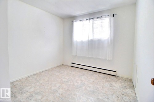 Bright room with light-colored flooring and a window dressed with white sheer curtains - 5109 49 Avenue, Andrew, AB - Indoor Photo Showing Other Room