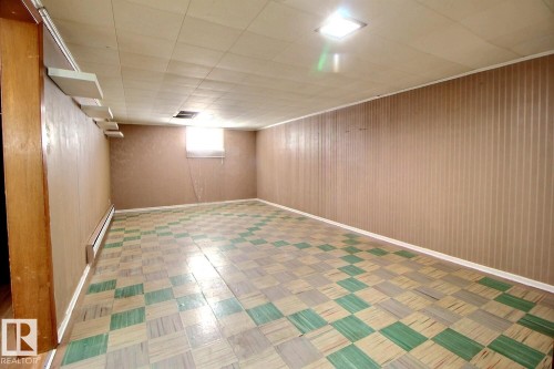 The property features a spacious room with a checkered floor pattern, light-toned paneled walls, and a recessed ceiling light fixture - 5109 49 Avenue, Andrew, AB - Indoor