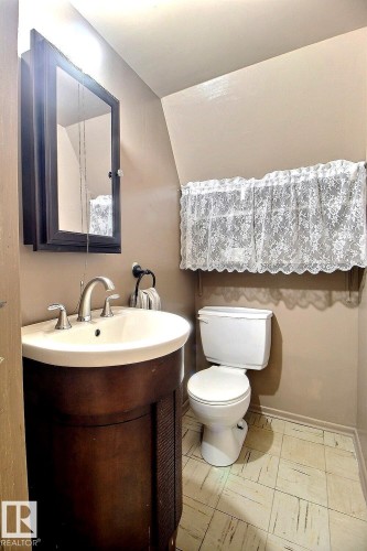 This bathroom features a contemporary dark wood vanity with an integrated white sink and a silver faucet - 5109 49 Avenue, Andrew, AB - Indoor Photo Showing Bathroom