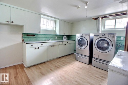 Laundry room featuring light-colored flooring, extensive cabinetry, and two front-loading laundry machines - 5109 49 Avenue, Andrew, AB - Indoor Photo Showing Laundry Room