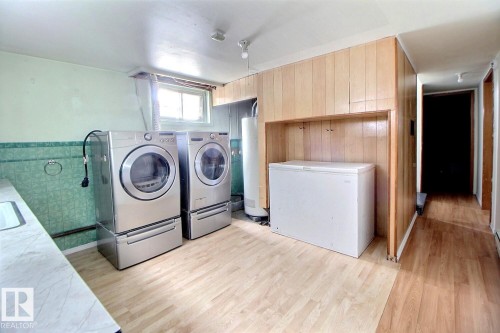 Laundry area with a window, wood paneled wall, and wood-look flooring - 5109 49 Avenue, Andrew, AB - Indoor Photo Showing Laundry Room