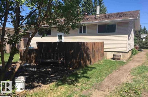 The property features a wood deck with a wooden swing, surrounded by mature trees - 5109 49 Avenue, Andrew, AB - Outdoor