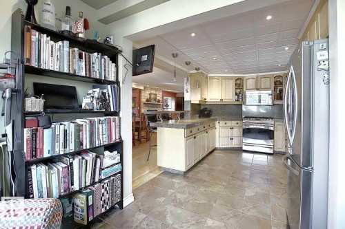 The kitchen features light-colored cabinetry, stainless steel appliances including a refrigerator and oven, a countertop with a stone-like appearance, and tiled flooring - 11126 52 Street, Edmonton, AB - Indoor Photo Showing Kitchen