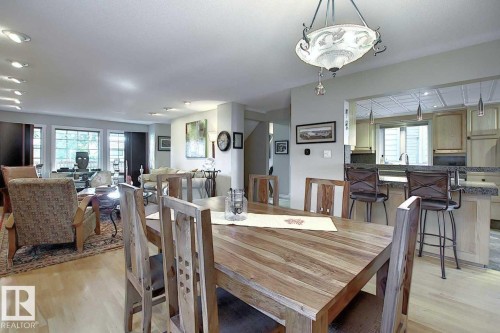 The dining area features a wooden table and chairs, illuminated by an ornate ceiling light fixture - 11126 52 Street, Edmonton, AB - Indoor Photo Showing Dining Room