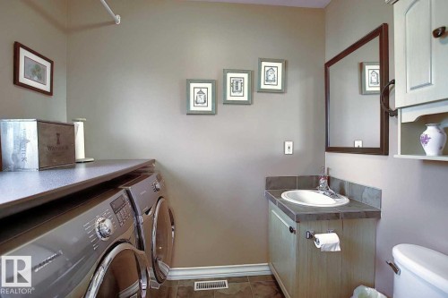 This utility space features a vanity with an integrated sink and mirror, along with laundry appliances and a countertop - 11126 52 Street, Edmonton, AB - Indoor Photo Showing Laundry Room