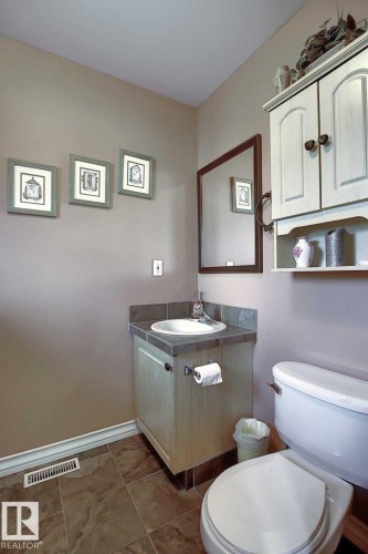 Bathroom featuring a vanity with a counter and sink, a wall-mounted mirror, and tile flooring - 11126 52 Street, Edmonton, AB - Indoor Photo Showing Bathroom